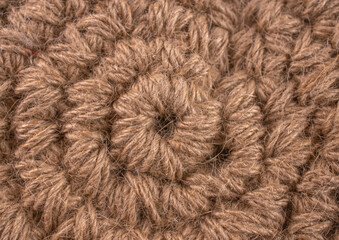 A close up of a knitted item with a brown color. The item is made of yarn and has a circular shape