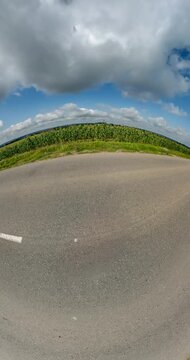vertical little planet transformation with curvature of space on road in blue sky with clouds