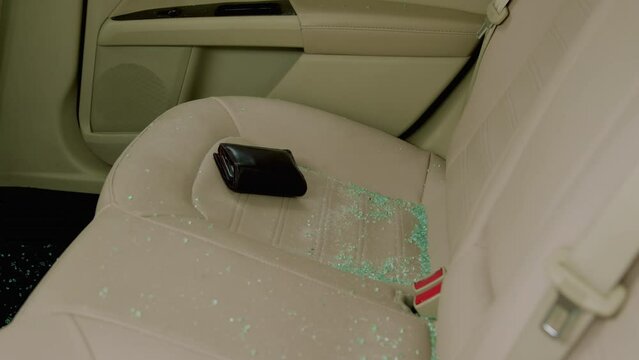 Aftermath of crime shattered glass remnants litter back seat of car. Broken pieces of glass from rear window are scattered across rear seat evidence of unlawful intrusion Broken shattered glass.