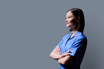 Portrait of young female nurse looking in profile on gray background
