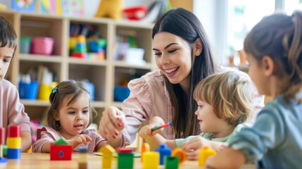 Young preschool female teacher playing with children at the table with colourful toys. Kids developing creativity and intelligence. - obrazy, fototapety, plakaty