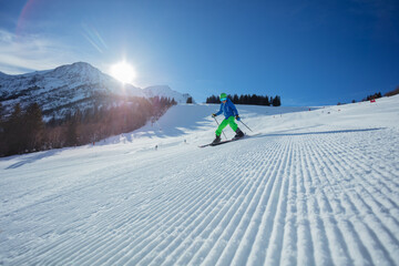 Skier kid glide on a sunny mountain slope in the morning sun - 773066315