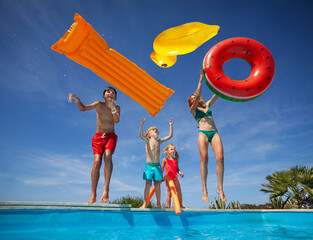 Family enjoys pool fun with floaties throw them in the air - 773067701
