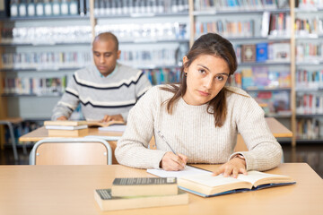 Portrait of young adult woman studying in at public library