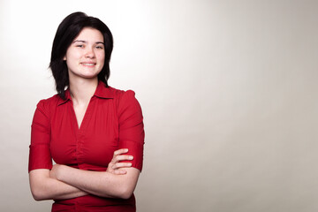 A woman in a red shirt is smiling and crossing her arms