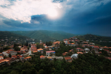 An aerial perspective of a small mountain town Sighnaghi with cloudy cumulus clouds in the atmosphere. The skyline is dotted with buildings, Kakheti, Georgia - 773072328
