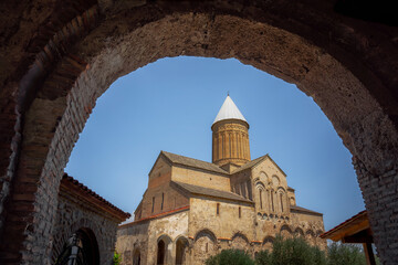 Saint George church glimpsed through an archway in the medieval architecture of Alaverdi Monastery Complex,, Kakheti, Georgia - 773072911