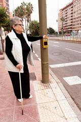 An elderly man uses a pedestrian crossing button on a city street. Smart city, comfort and safety...