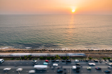 Road and railway track along coast at sunset over Indian ocean. Train arriving in Colombo, Sri Lanka..
