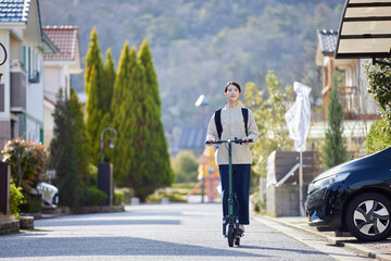 住宅街を電動キックボードで移動する日本人の女性