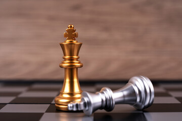 Motivational business and management concept. Golden and silver chess pieces placed on a chessboard. Blurred styled background.