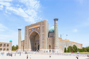 Registan square. Sher-Dor Madrasah, ornamented with verses from Q'ran (verses in Arabic language from Koran, Islam Holy Book). Crowd of tourists in front. April 24, 2023. Samarkand. Uzbekistan