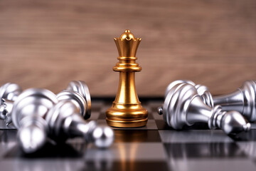 Motivational business and management concept. Golden and silver chess pieces placed on a chessboard. Blurred styled background.
