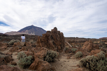 Woman sitting on rocks with Mount Teide in background at Teide National Park, Tenerife