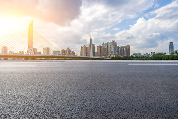 Asphalt road and bridge with modern city buildings at sunset - obrazy, fototapety, plakaty