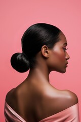 Profile view of a woman with a sleek low bun hairstyle against a soft pink backdrop