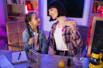 Caucasian mother making chemical experiments or tests with smart cute daughter. Young woman and...