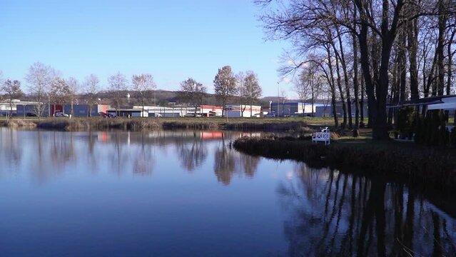 Footage taken from a shore of a lake with cars and buildings on other side