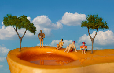 Miniature people on holiday on a butternut pumpkin in the sky.  Abstract tourism concept.