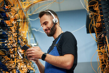 Young man is working with internet equipment and wires in server room