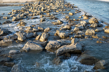 A rocky shoreline with a stream of water running through it