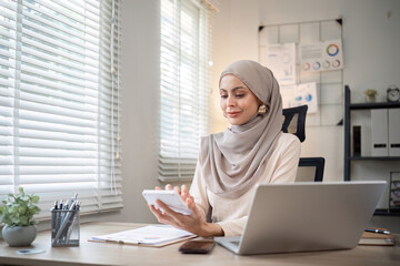 Attractive Muslim accounting business woman working using laptop in modern office