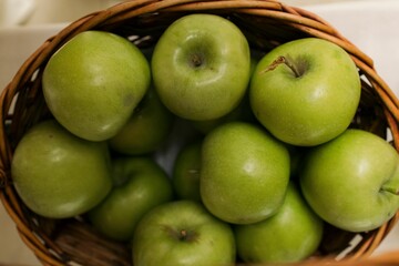 Closeup shot of a wicker basket with a pile of green apples