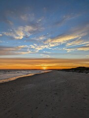 Scenic beach view of a stunning sunset with an array of clouds on the distant horizon