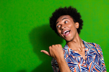 Portrait of interested man wearing print shirt pointing finger billboard excited give tips for beginners isolated on green color background