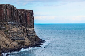 Beautiful rocky cliff over blue water in Isle of Skye, Scotland, UK