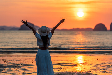 Happy woman traveler, arms rised, enjoying sunset at sea, Phuket and Krabi travel sounthern...