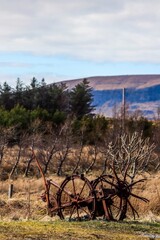 Fototapeta na wymiar Aged, rust-covered plow on a rural field in Isle of Skye, Scotland, UK