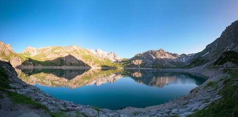 the mountains around a lake are reflected in the water and sky