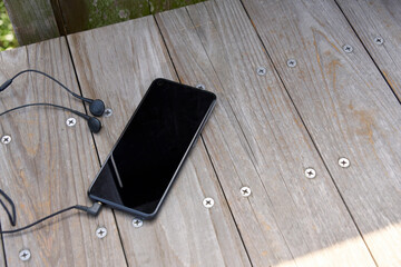 木のベンチに置かれた音楽再生中のスマートフォン