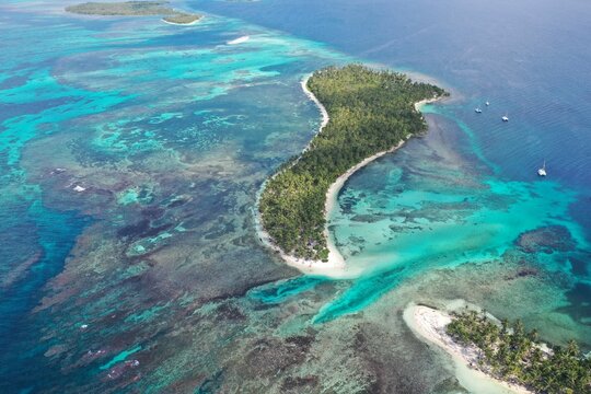 an aerial view of the blue waters and shore of a small island
