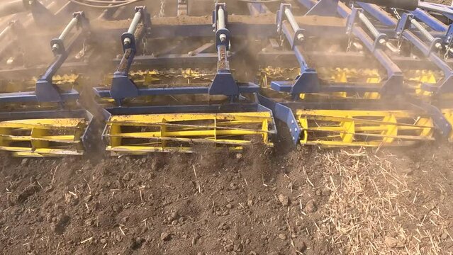Large tractor with agricultural machinery cultivates the arable land and prepares the soil for sowing agricultural crops, slow motion