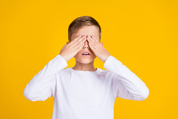 Photo of impressed scared boy wear white shirt arms closed eyes empty space isolated yellow color...