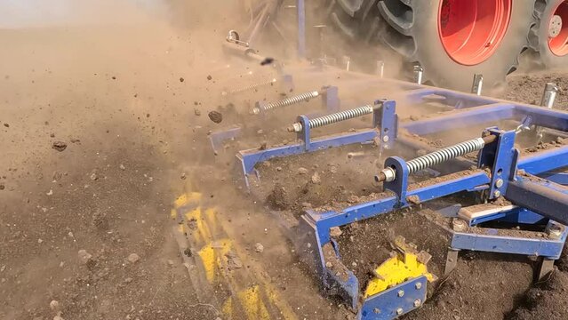 Large tractor with agricultural machinery cultivates the arable land and prepares the soil for sowing agricultural crops, slow motion