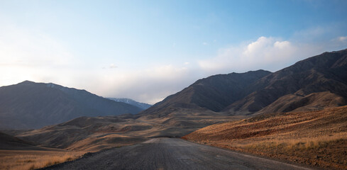 Fototapeta na wymiar Kunlun Mountains in China. Mountain landscape background. Natural patterns on earth. Country road passing through the mountains during sunset.
