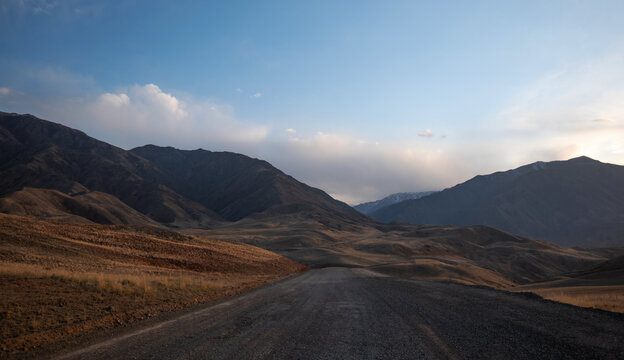 Kunlun Mountains in China. Mountain landscape background. Natural patterns on earth. Country road passing through the mountains during sunset.