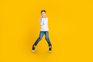 Fototapeta na wymiar Full length photo of impressed excited boy wear white shirt jumping arms hands cheeks empty space isolated yellow color background