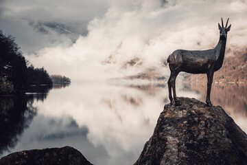 Majestic bronze statue of a deer stands atop a picturesque rock formation