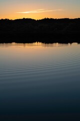 A vertical shot of ripples on a tranquil lake at sunset