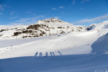 Closeup of the shadow of people on a snow-covered mountain  under the  blue sky