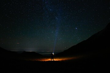 Human standing at the end of a road, captivated by the starry night sky above