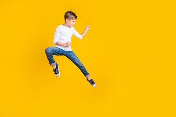 Full length photo of lucky strong boy wear white shirt jumping high enjoy karate empty space isolated yellow color background