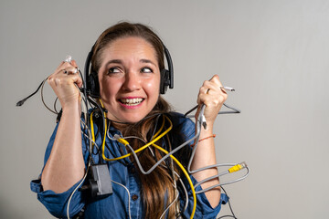 Mujer entre un montón de cables en expresión de problemas con la tecnología. Dificultades técnicas con computadoras y tecnología