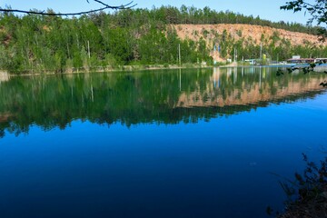 Fototapeta premium Closeup of a beautiful lush green field and tranquil water under the blue sky in Jaworzno