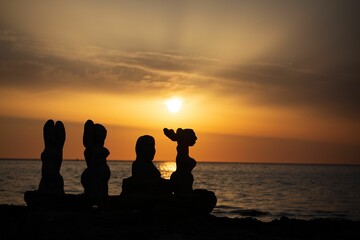 silhouettes of stacked pebbles against a sunset background