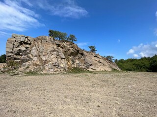 Large rock in a deserted and uncultivated area against a cloudy blue sky